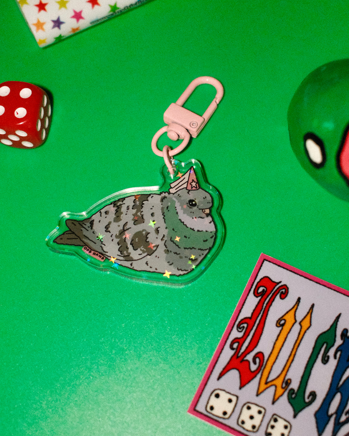 Keychain with a seal design on a green surface with dice and cards.