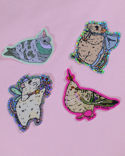 Four cute animal stickers featuring a cat, mouse, rabbit, and bird with colorful glittery holographic borders, displayed on a pink textured background.